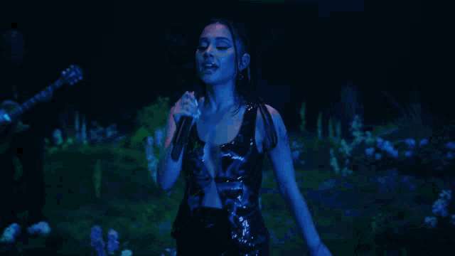 a woman singing into a microphone with a man playing drums in the background
