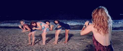 a woman is taking a picture of her friends on the beach at night