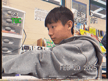 a boy is sitting at a desk with a tbc logo on the top left