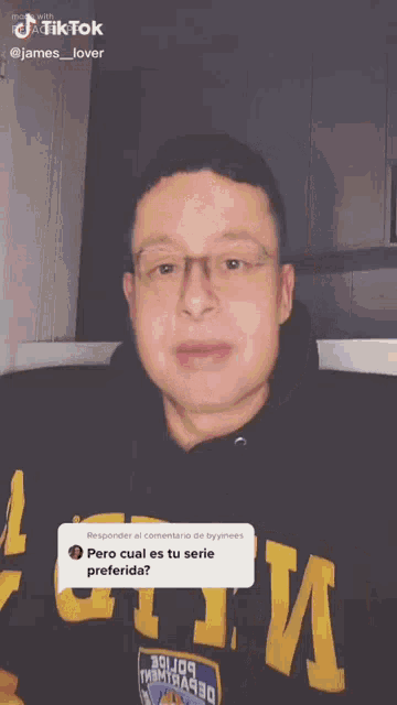 a man wearing glasses and a black hoodie is making a funny face and giving a thumbs up .