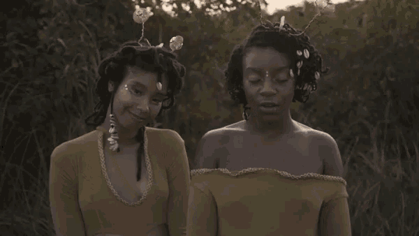 two women with dreadlocks are standing next to each other in the grass .
