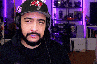 a man wearing a buccaneers hat and headphones looks at the camera