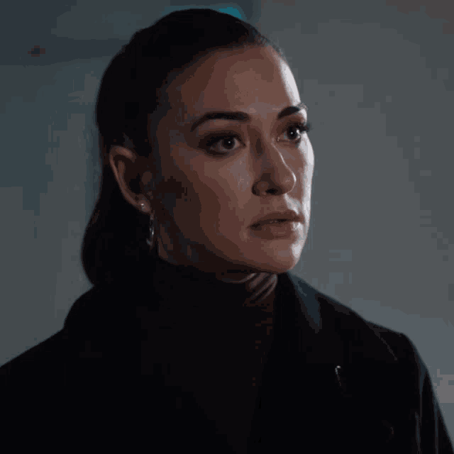 a close up of a woman wearing hoop earrings and a black jacket
