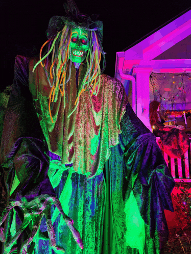 a statue of a witch with dreadlocks is lit up with neon green lights