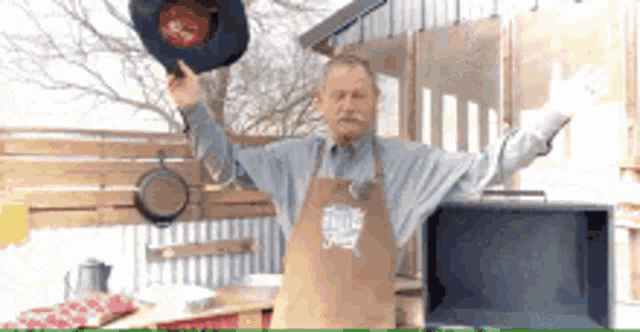 a man in an apron is holding a frying pan in his hand