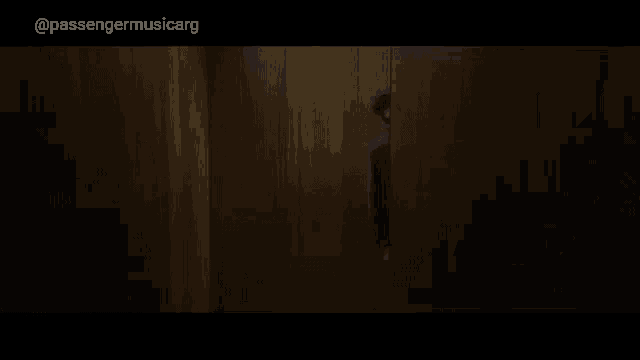 a man in a purple sweater is peeking out from behind a wooden wall .