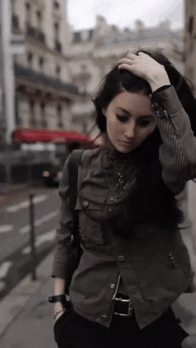 a woman in a green jacket is walking down a street