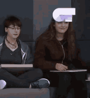 a boy and a girl are sitting on a couch in front of a j logo .