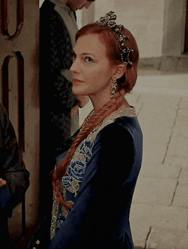 a woman with red hair wearing a blue dress and tiara