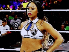 a woman in a crop top and tie is standing in a ring .