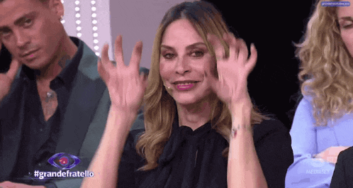 a woman sitting in front of a microphone with #grandefratello written on the bottom