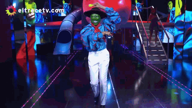 a man in a mask is on a stage with eltrecetv.com in the corner
