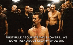 a shirtless man stands in front of a group of men and says first rule about steamy showers we dont talk about steamy shower