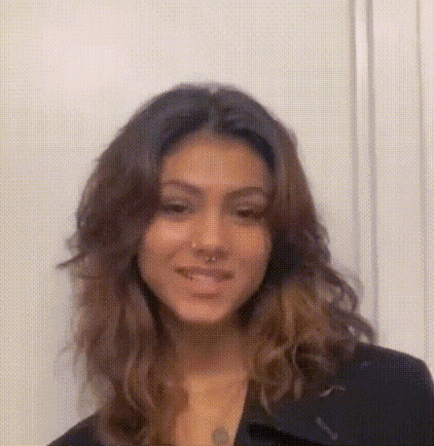 a close up of a woman 's face with a nose ring and long hair .