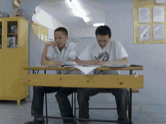 two boys sit at a desk with one wearing a shirt that says ' zebra ' on it