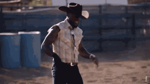 a man in a cowboy hat is dancing in a rodeo arena