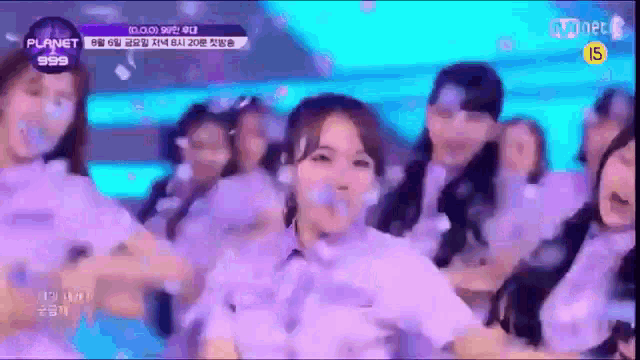 a group of girls are dancing on a stage in front of a sign that says planet 999 .
