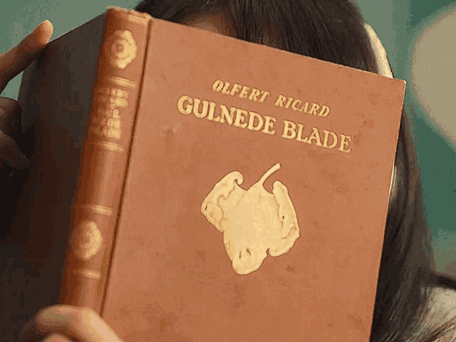 a woman holding a book called guinede blade