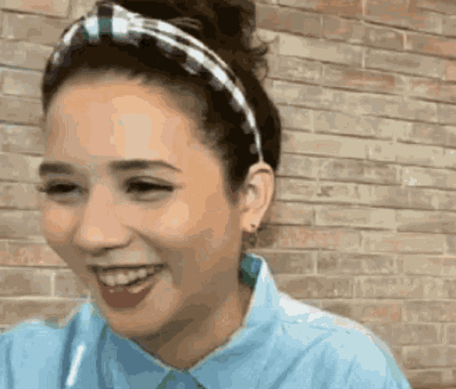 a woman wearing a headband and a blue shirt is smiling .