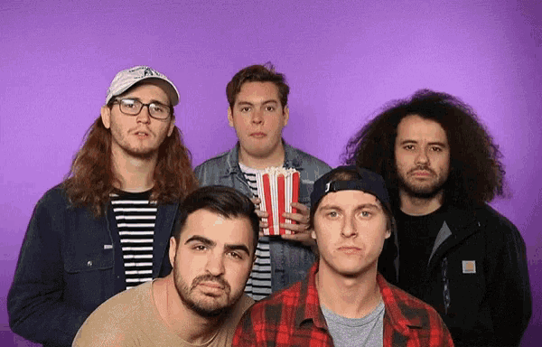 a group of men standing in front of a purple background