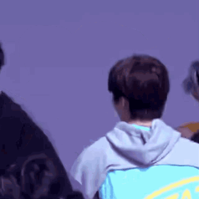 a man in a blue hoodie is standing next to another man in a black shirt .