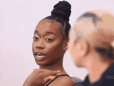 a woman with a bun on her head is talking to another woman while another woman looks on .