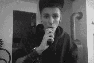 a black and white photo of a person smoking a cigarette .