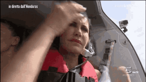 a woman in a life jacket is sitting in a car with the words in diretta dall ' honduras written above her
