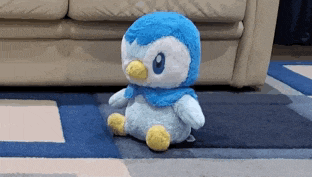 a stuffed penguin is sitting on a blue rug