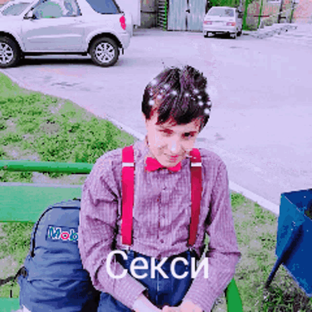 a man wearing suspenders and a bow tie is sitting on a bench with a backpack that says mobil