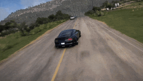a ford mustang is driving down a road with two other cars