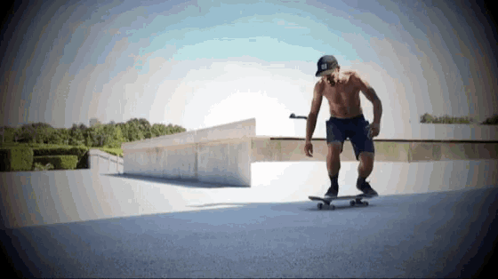 a shirtless man rides a skateboard down a ramp