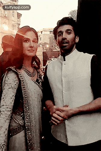 a man and a woman standing next to each other holding hands