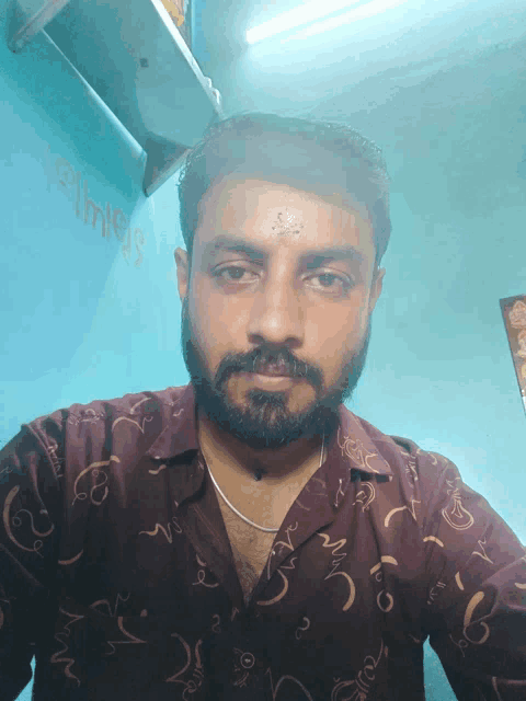 a man with a beard is taking a selfie in front of a blue wall that says ' a ' on it