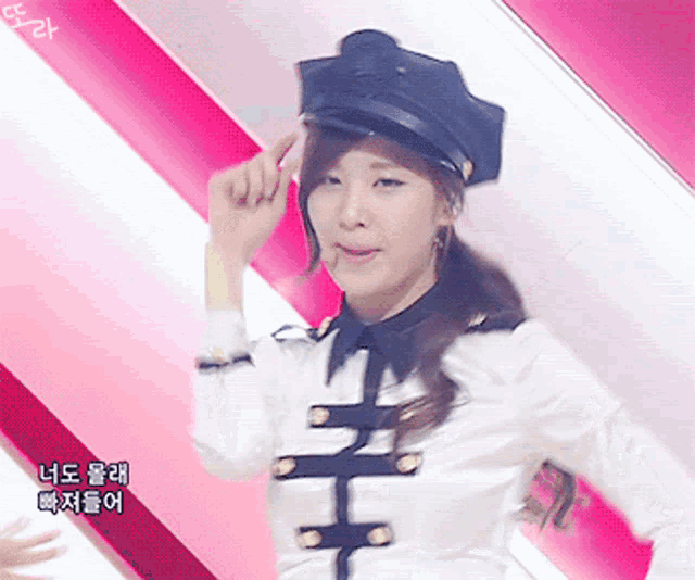 a woman wearing a black hat and a white shirt is standing in front of a pink and white background