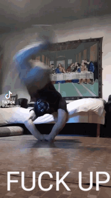 a person is doing a handstand in front of a painting that says fuck up