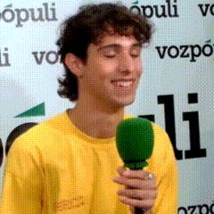 a man in a yellow shirt is holding a green microphone and smiling