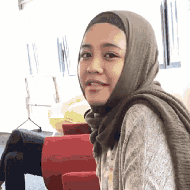 a woman wearing a hijab and a scarf is smiling for the camera