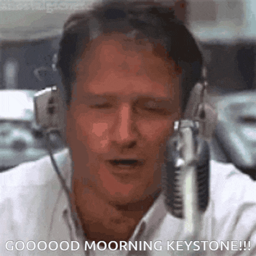 a man is wearing headphones and singing into a microphone with his eyes closed .