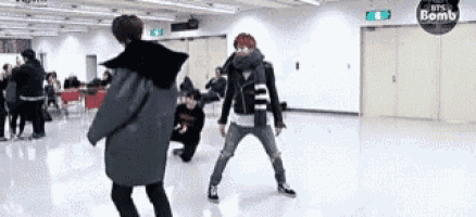 a group of people are dancing in a room with a sign that says bts bomb on it .