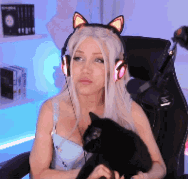 a woman wearing cat ears holds a black cat in her lap