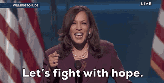 a woman says let 's fight with hope in front of a flag