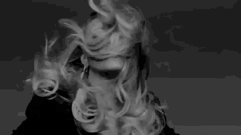 a black and white photo of a woman with her hair blowing in the wind
