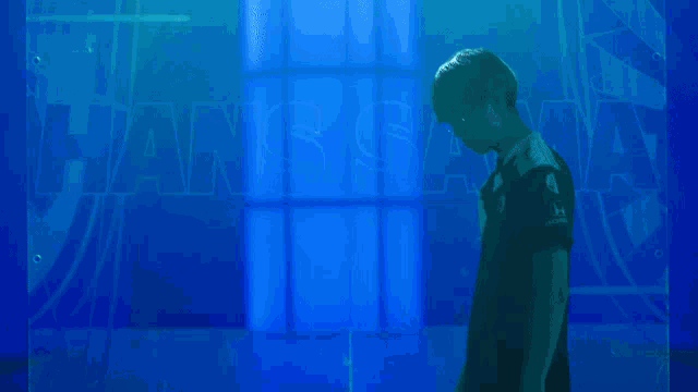 a man wearing glasses is standing in front of a blue wall
