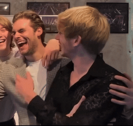 a group of young men are laughing and hugging