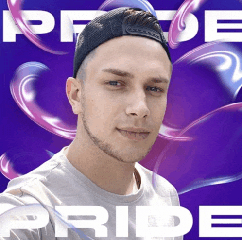 a man wearing a hat is standing in front of a purple background that says pride