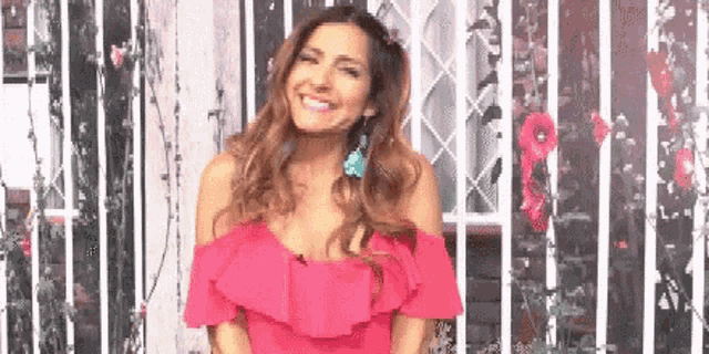 a woman in a pink off the shoulder dress is smiling .