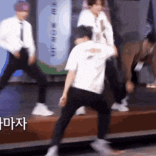 a group of men are dancing on a stage with korean writing on the bottom .