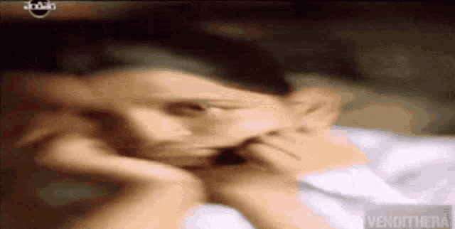 a blurred image of a woman laying on a bed with the word vendthera on the bottom left