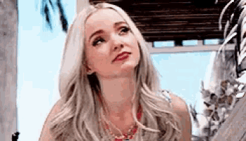 a woman with blonde hair and a red necklace is looking up at the sky .